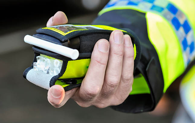 Photo of a policeman's hand holding a breathalyser