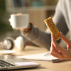 Photo of someone with a cereal bar in one hand and a cup in the other