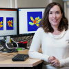 Photo of Lori Hoagland with computer screens showing hyperspectral images of plants in the bakground.